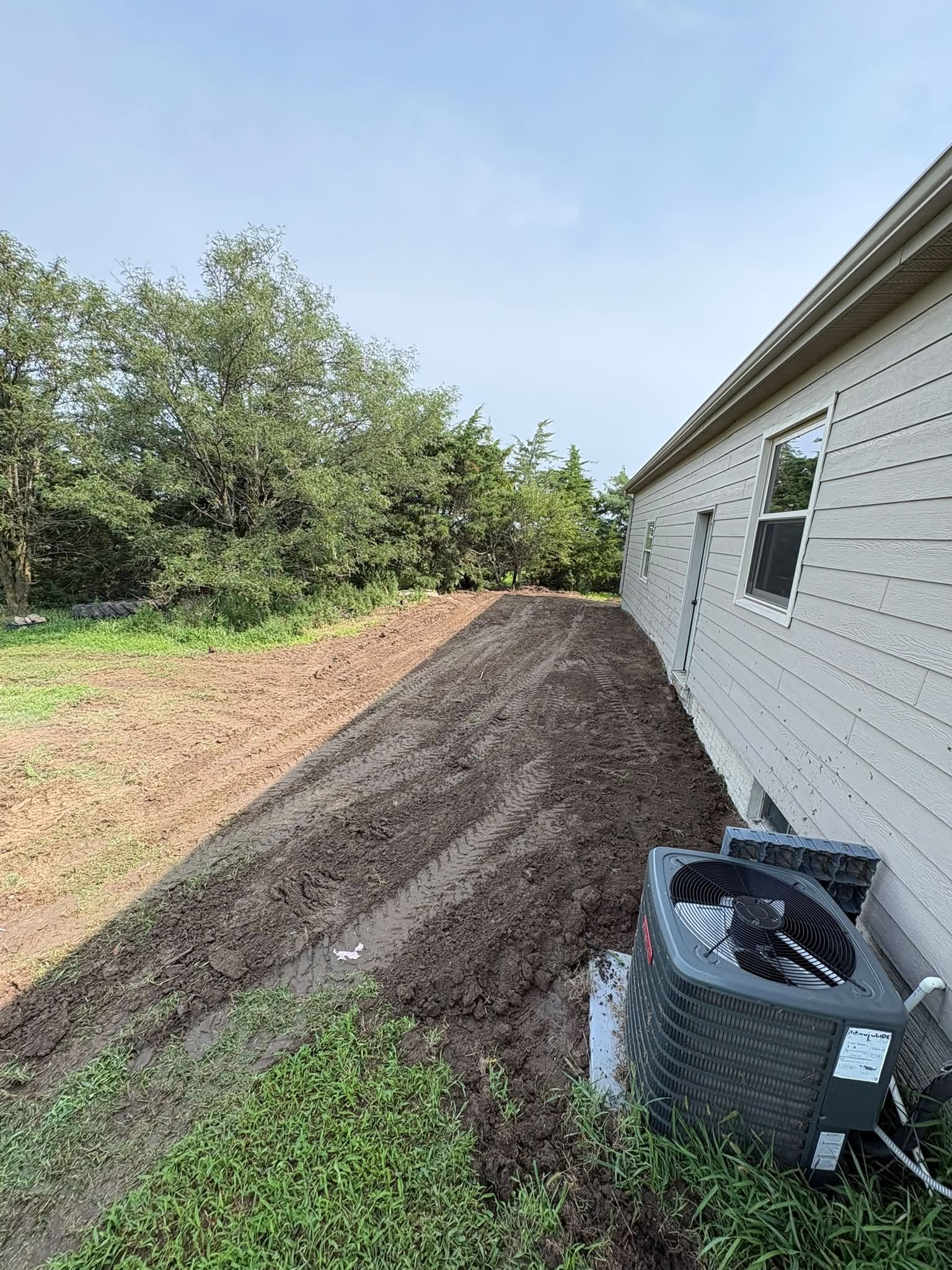 Graded residential site alongside a home prepared for a concrete slab